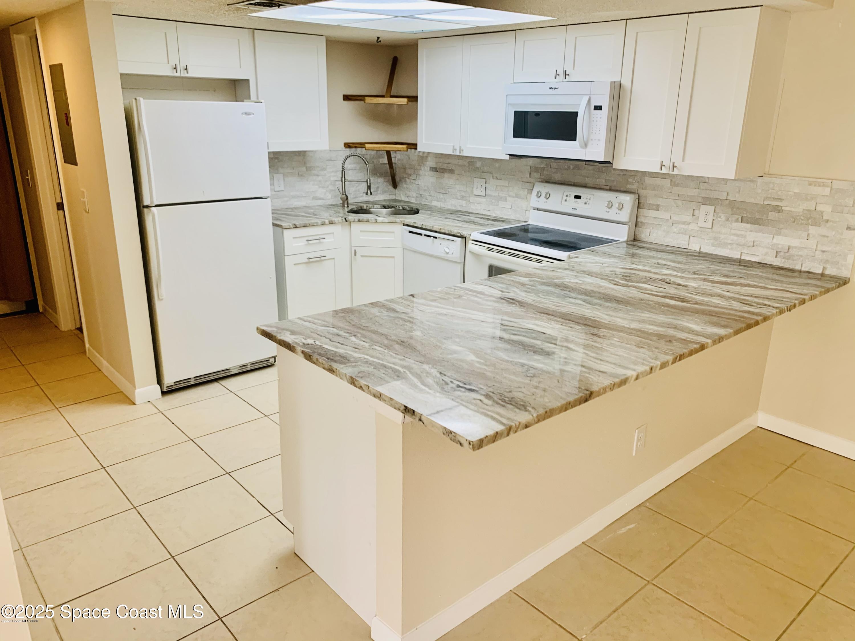 1648 Sunny Brook Lane, Unit M202 Palm Bay, FL 32905 - Photo 2 of 15 a kitchen with stainless steel appliances granite countertop a refrigerator a stove a sink and a counter