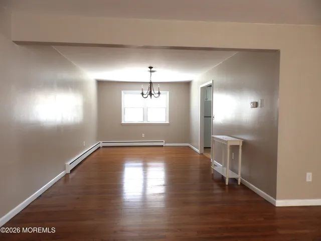 a view of an empty room with window and wooden floor