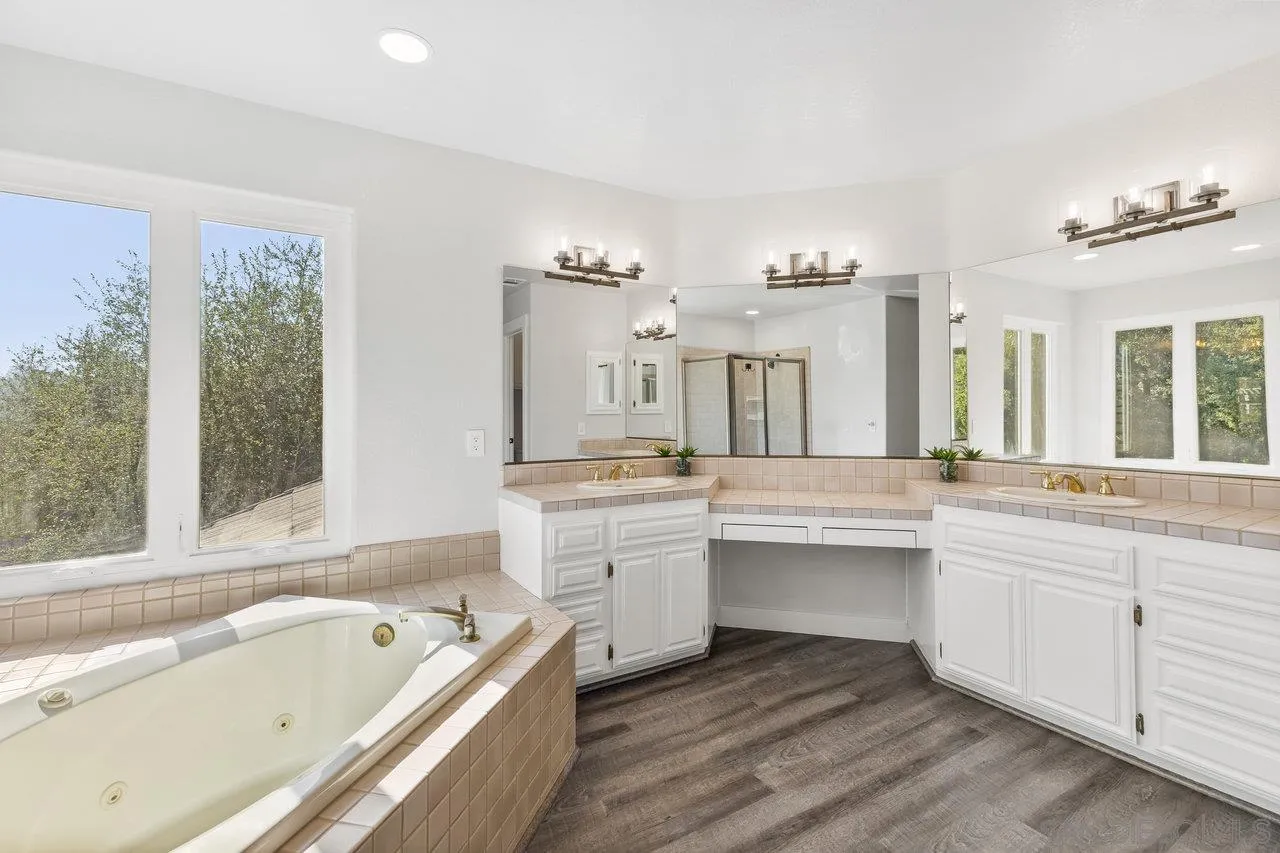 15931 Litten Way Ramona, CA 92065 - Photo 23 of 43 a bathroom with a bathtub a double vanity sink and a large mirror