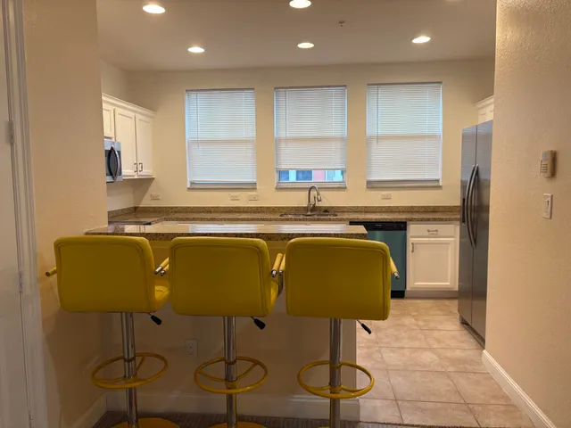 a kitchen with stainless steel appliances granite countertop a chairs a sink and a microwave