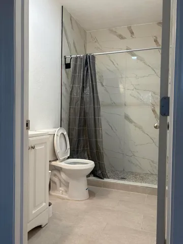 a bathroom with a shower a toilet and a window
