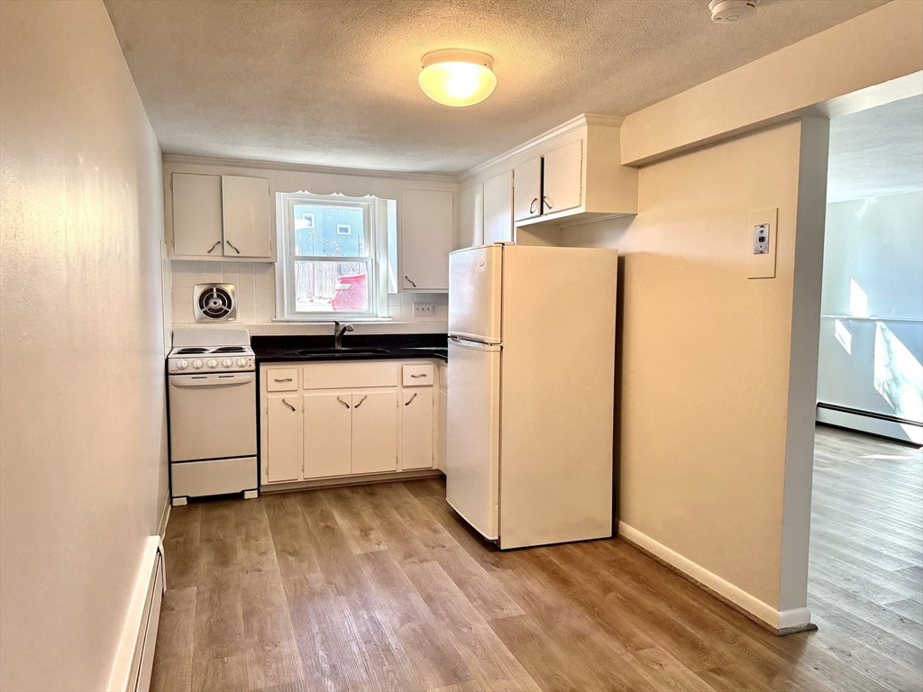 206 High Street, Unit 7 Waltham, MA 02453 - Photo 2 of 17 a kitchen with granite countertop a refrigerator a sink and white cabinets