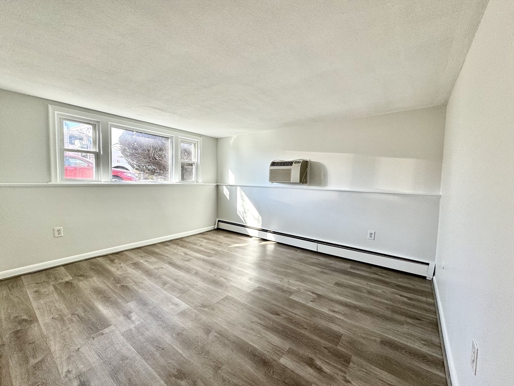 206 High Street, Unit 7 Waltham, MA 02453 - Photo 3 of 17 an empty room with wooden floor and window
