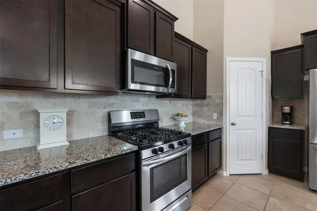 a kitchen with stainless steel appliances granite countertop a stove a microwave and a refrigerator