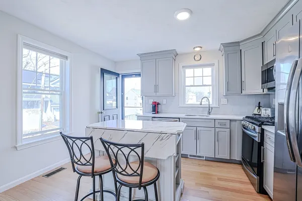 a kitchen with stainless steel appliances granite countertop a stove a sink dishwasher a dining table and chairs with wooden floor