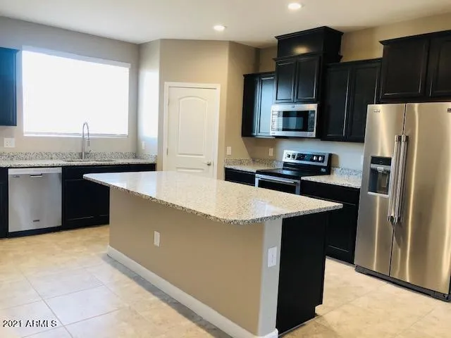 a kitchen with stainless steel appliances a sink a stove a refrigerator a center island and a window