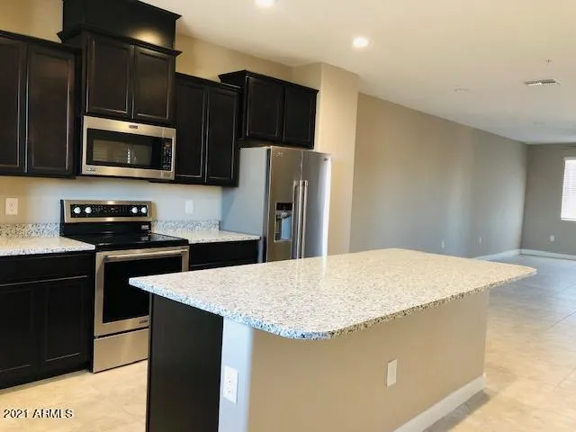 a kitchen with granite countertop a refrigerator and a stove top oven