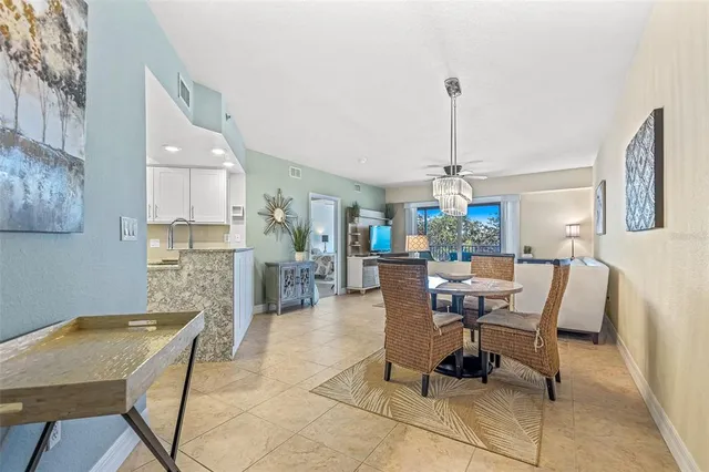 a dining room filled a chandelier and kitchen view