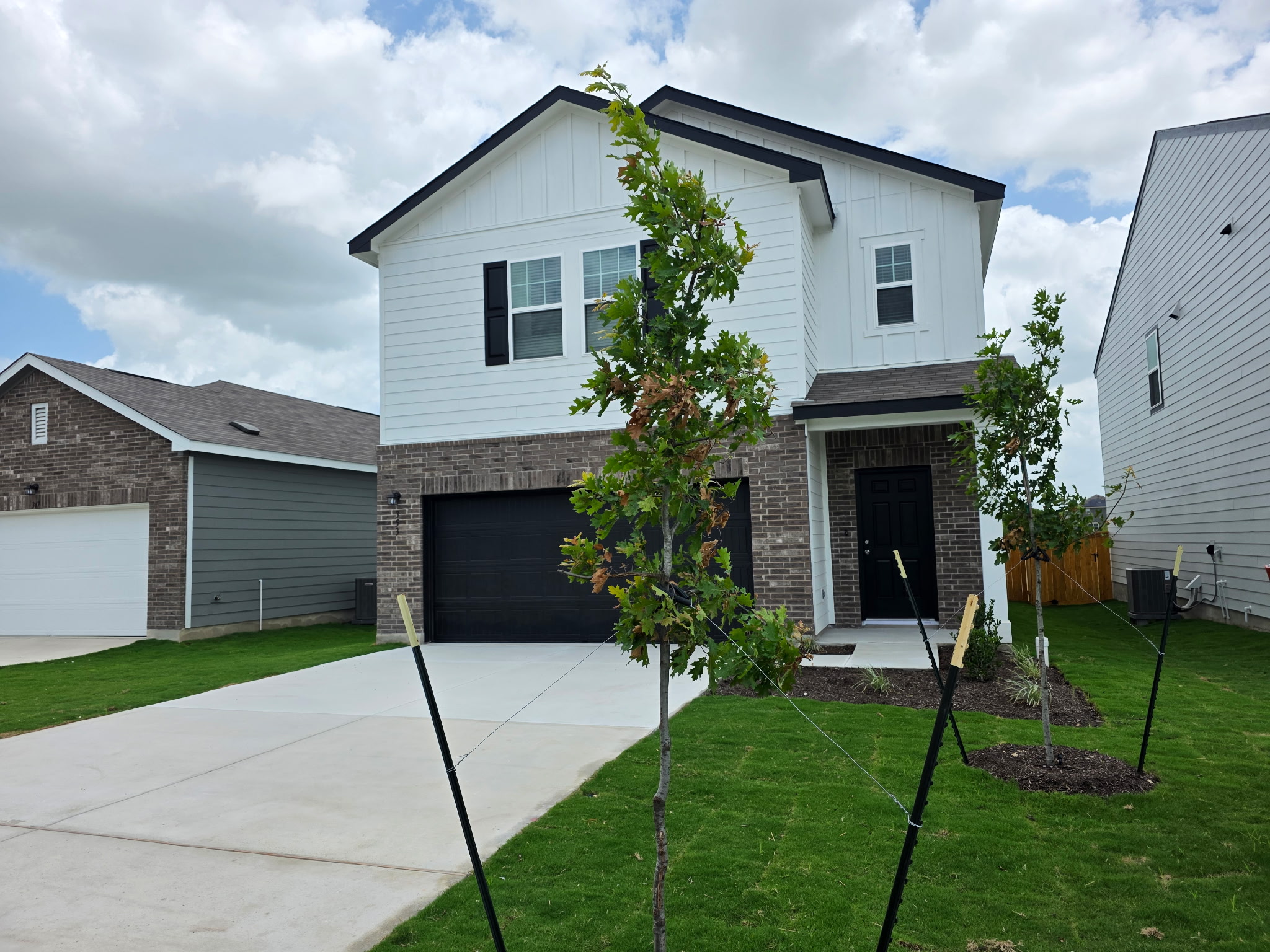 353 Enforcer Loop Jarrell, TX 76537 - Photo 2 of 21 View of front of home with brick siding, board and batten siding, central AC unit, and driveway