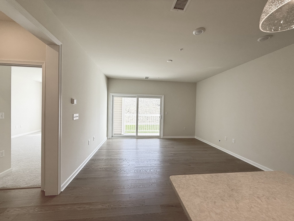 6 Stratton Drive, Unit 110 Woburn, MA 01801 - Photo 3 of 26 an empty room with wooden floor and windows