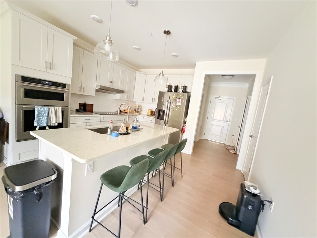 6 Stratton Drive, Unit 110 Woburn, MA 01801 - Photo 7 of 26 a kitchen with a dining table chairs and white cabinets