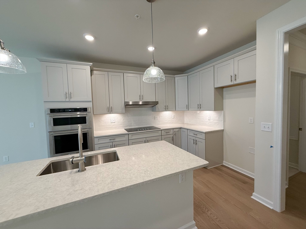6 Stratton Drive, Unit 110 Woburn, MA 01801 - Photo 8 of 26 a kitchen with a refrigerator a stove a microwave and a center island