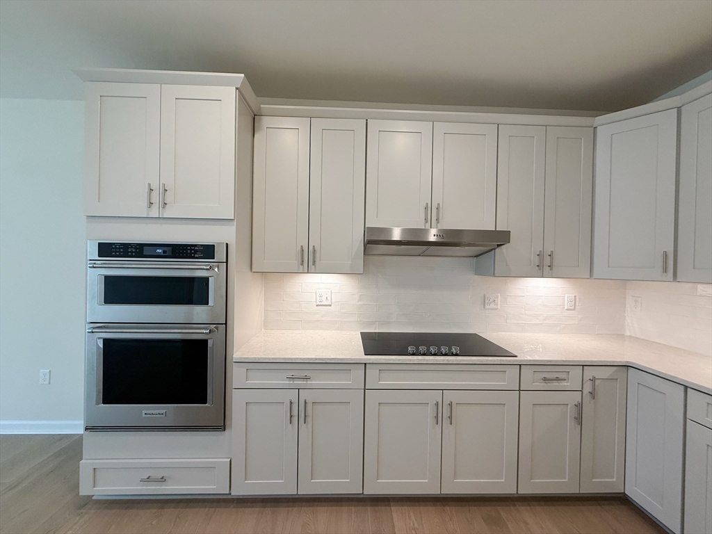6 Stratton Drive, Unit 110 Woburn, MA 01801 - Photo 10 of 26 a kitchen with granite countertop white cabinets and stainless steel appliances