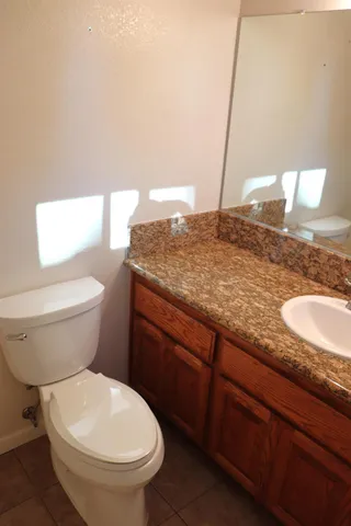 a bathroom with a granite countertop toilet sink and mirror