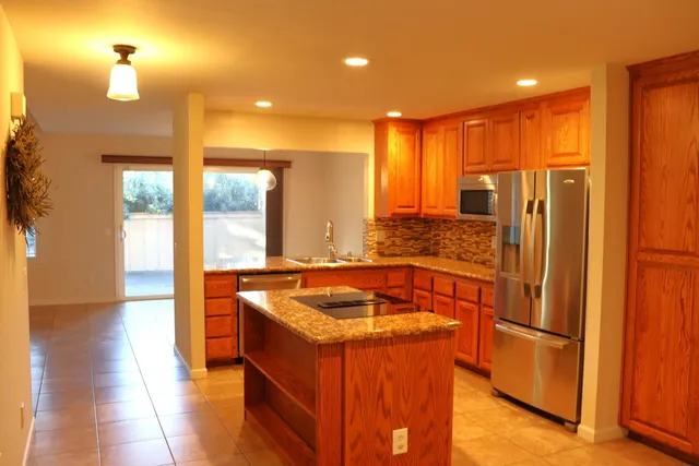 a kitchen with stainless steel appliances granite countertop a sink and a refrigerator