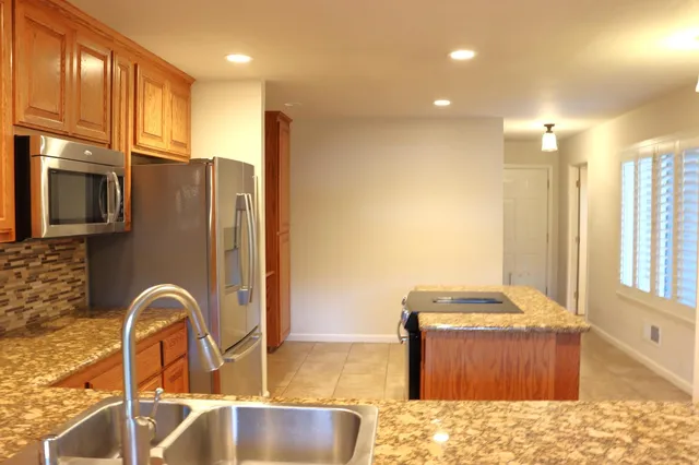 a kitchen with stainless steel appliances granite countertop a sink a stove and a refrigerator