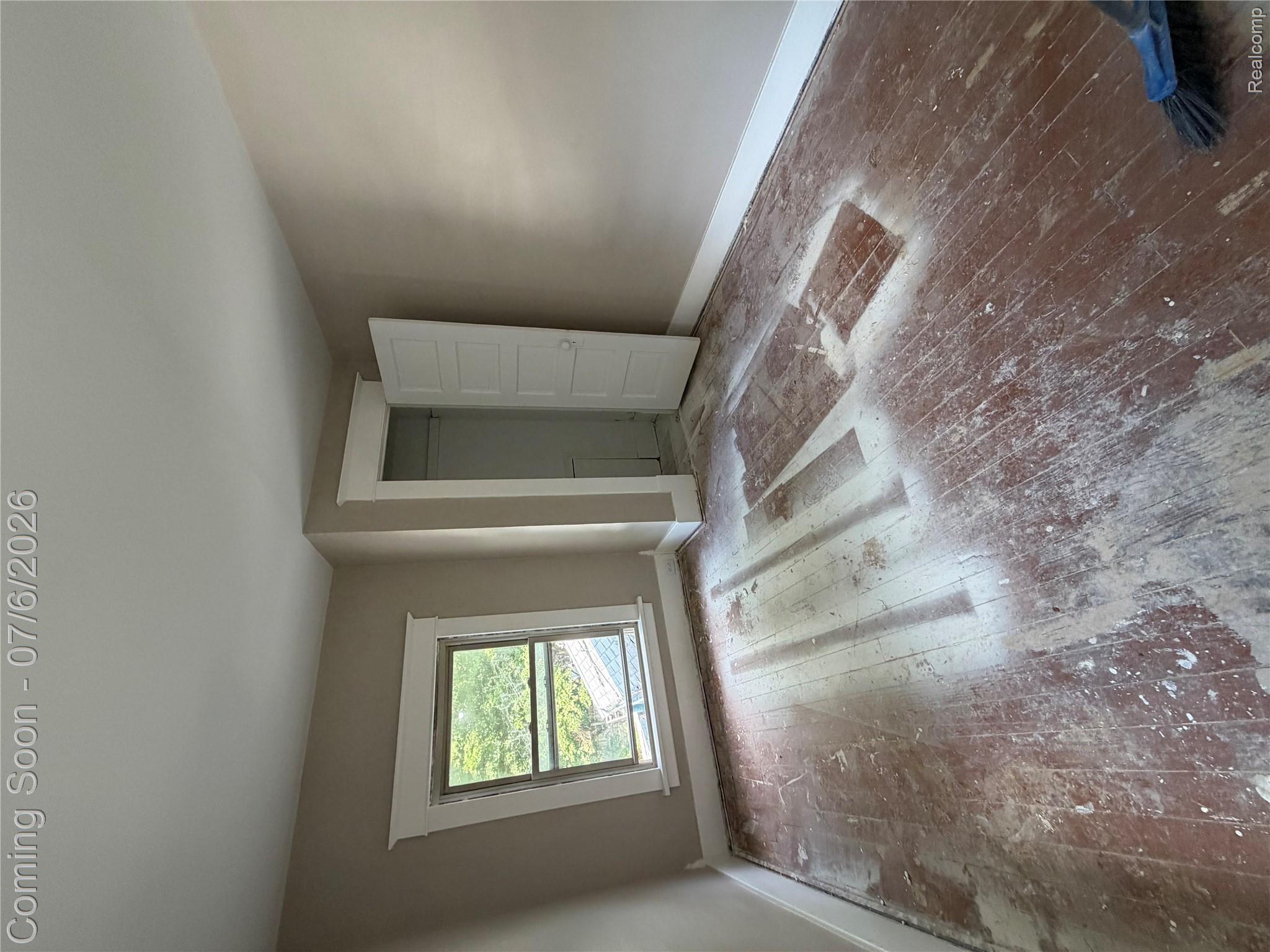 808 Division Street Owosso, MI 48867 - Photo 14 of 25 Interior room featuring distressed wood-finish flooring, a single window with white trim, and a white paneled door revealing a closet