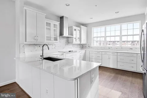 a kitchen with white cabinets appliances a sink and a window