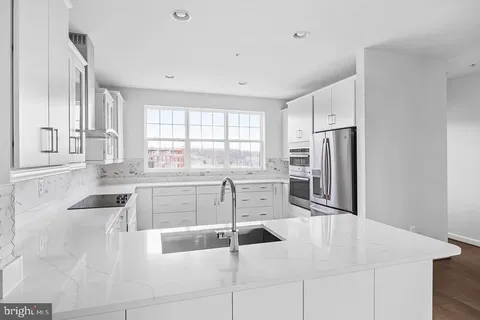 a kitchen with a refrigerator a stove and white cabinets with wooden floor