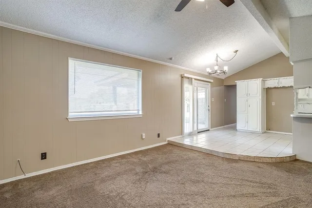 an empty room with chandelier fan and windows
