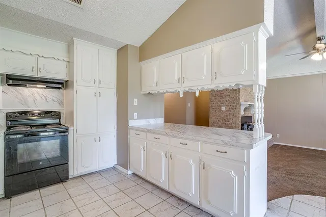 a kitchen with granite countertop white cabinets and stainless steel appliances