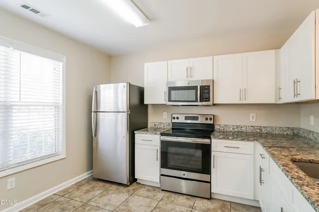 a kitchen with white cabinets and stainless steel appliances