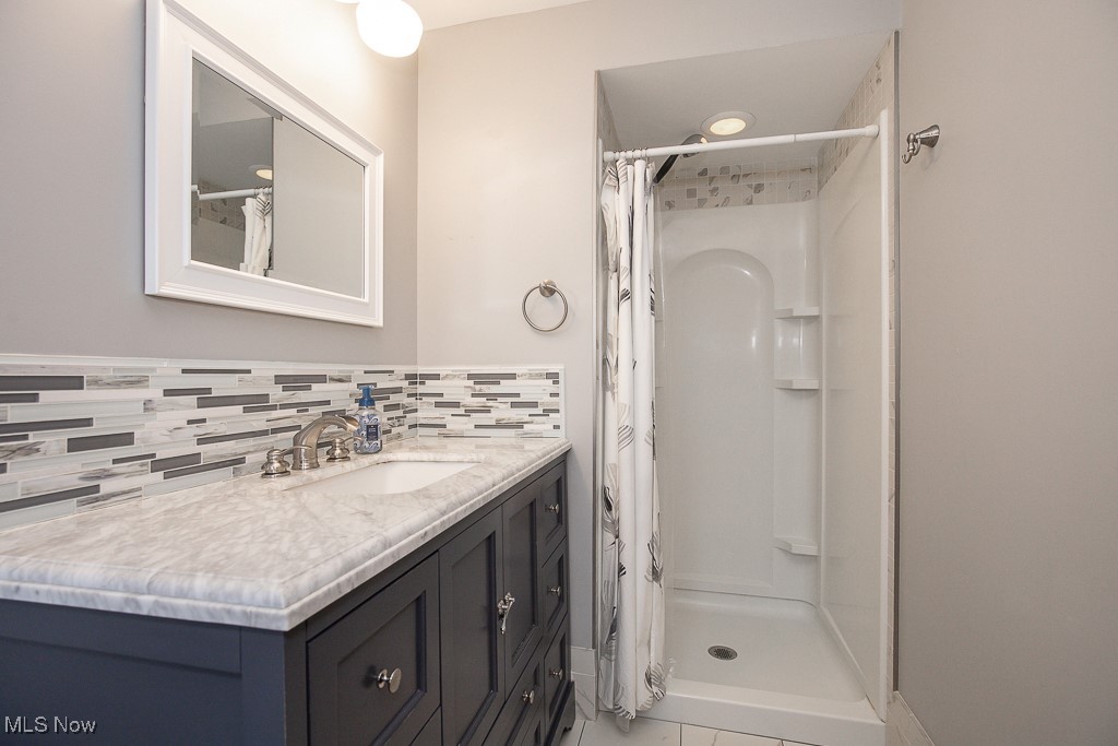 2969 Center Road Avon, OH 44011 - Photo 21 of 33 Bathroom featuring a shower with curtain, vanity, and decorative backsplash