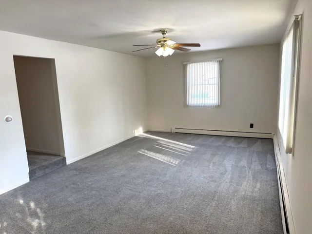 an empty room with a chandelier fan and windows