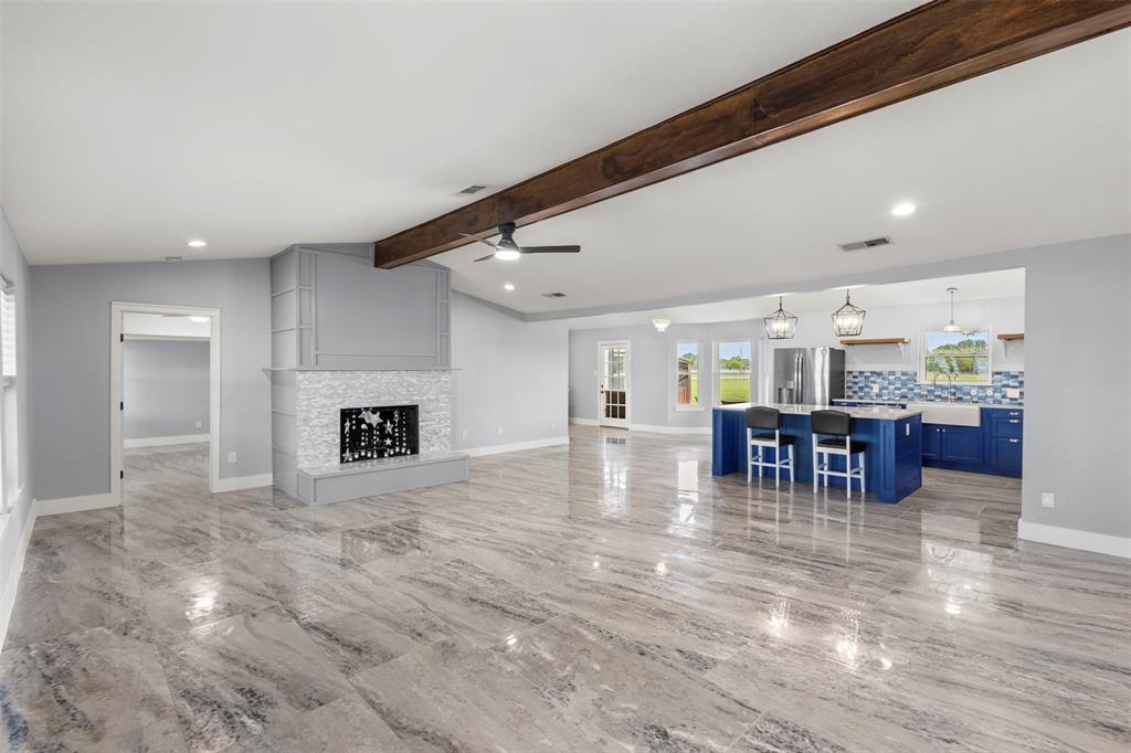 6754 Raymond Road Kaufman, TX 75142 - Photo 2 of 38 Spacious open-concept interior featuring wood-finish flooring, a contemporary fireplace with a mosaic tile surround, and a kitchen with a blue island and matching cabinetry