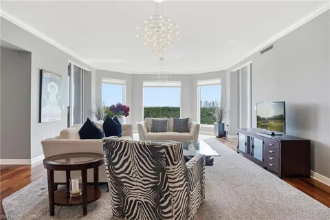 a living room with furniture a large window and a chandelier