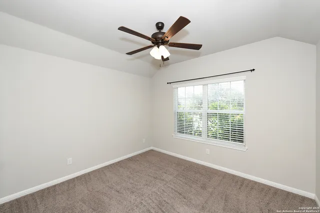 an empty room with a window and a ceiling fan