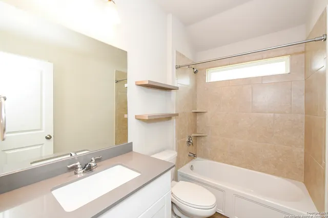 a bathroom with a granite countertop bathtub shower sink vanity and toilet