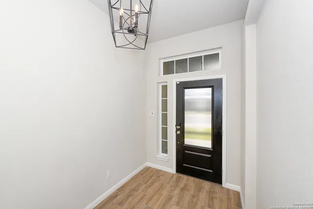 a view of a hallway with wooden floor and a bathroom