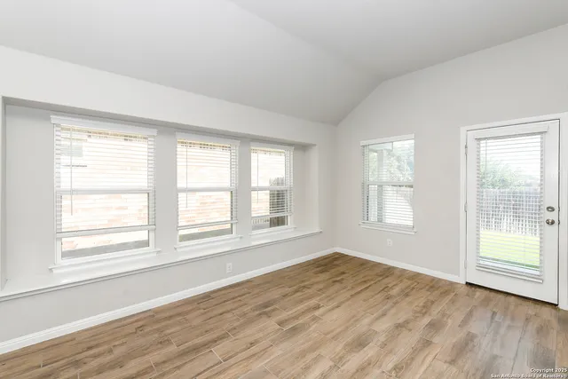 a view of an empty room with wooden floor and a window