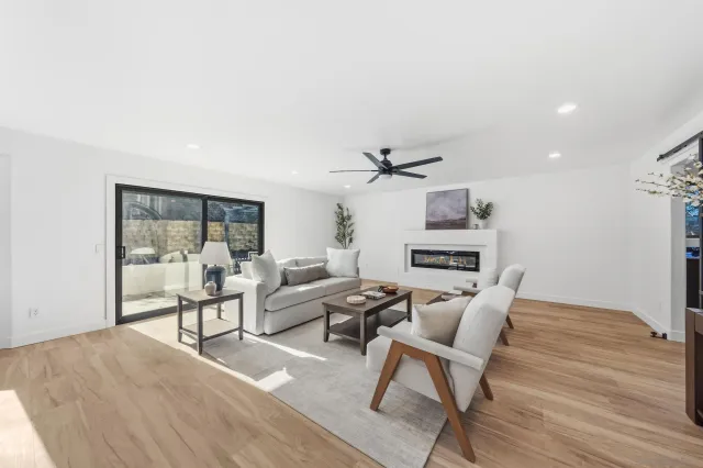 a living room with furniture ceiling fan and a large window