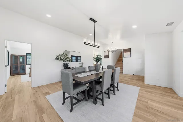 a dining room with wooden floor a chandelier a wooden table and chairs