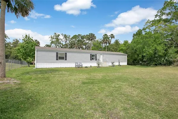 a front view of house with yard and trees in the background