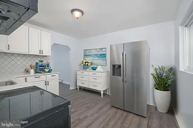 a kitchen with stainless steel appliances a refrigerator a sink a stove and white cabinets