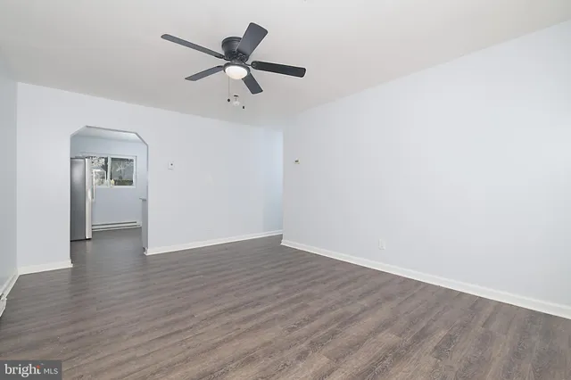 a view of a big room with wooden floor a ceiling fan and windows