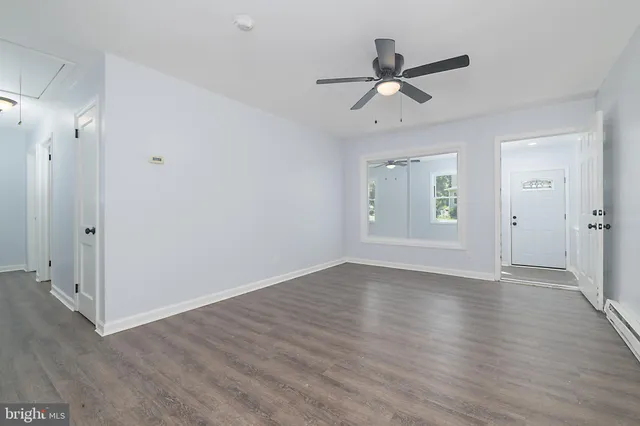 a view of an empty room with wooden floor and a ceiling fan