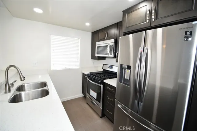 a kitchen with stainless steel appliances granite countertop a refrigerator a sink a stove and island