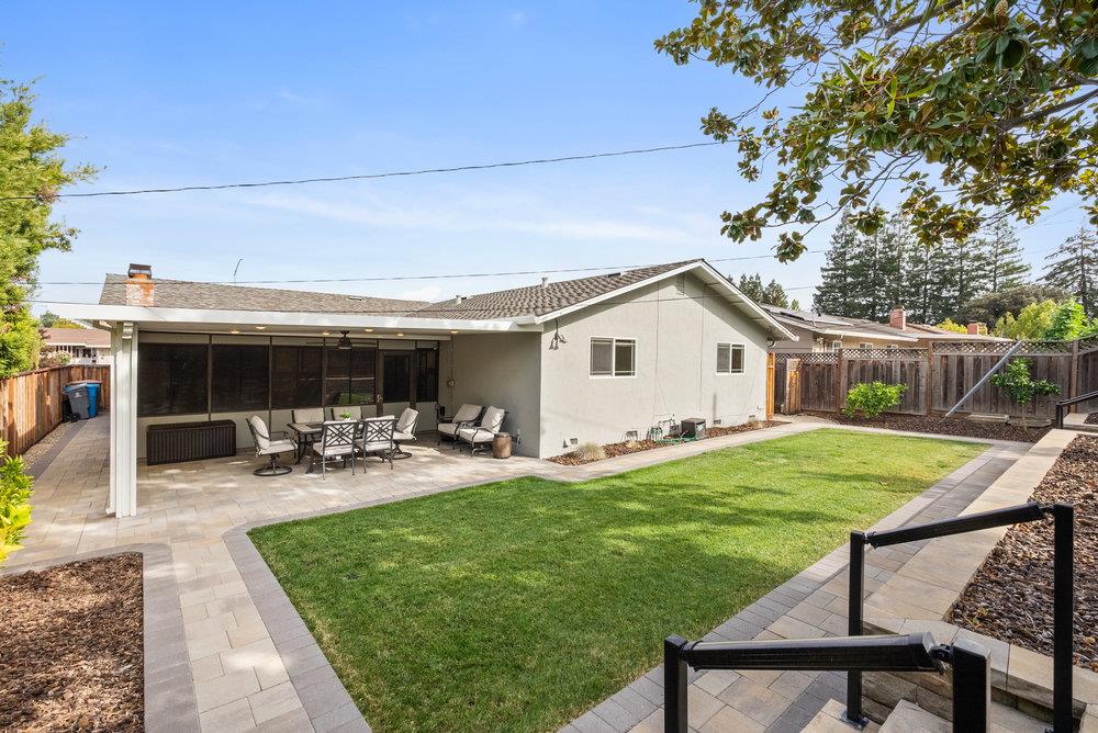 1121 Yorkshire Drive Cupertino, CA 95014 - Photo 25 of 30 a view of a backyard with table and chairs under an umbrella with wooden fence