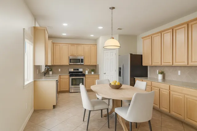 a kitchen with stainless steel appliances granite countertop a stove top oven a refrigerator a sink and a dining table with wooden floor