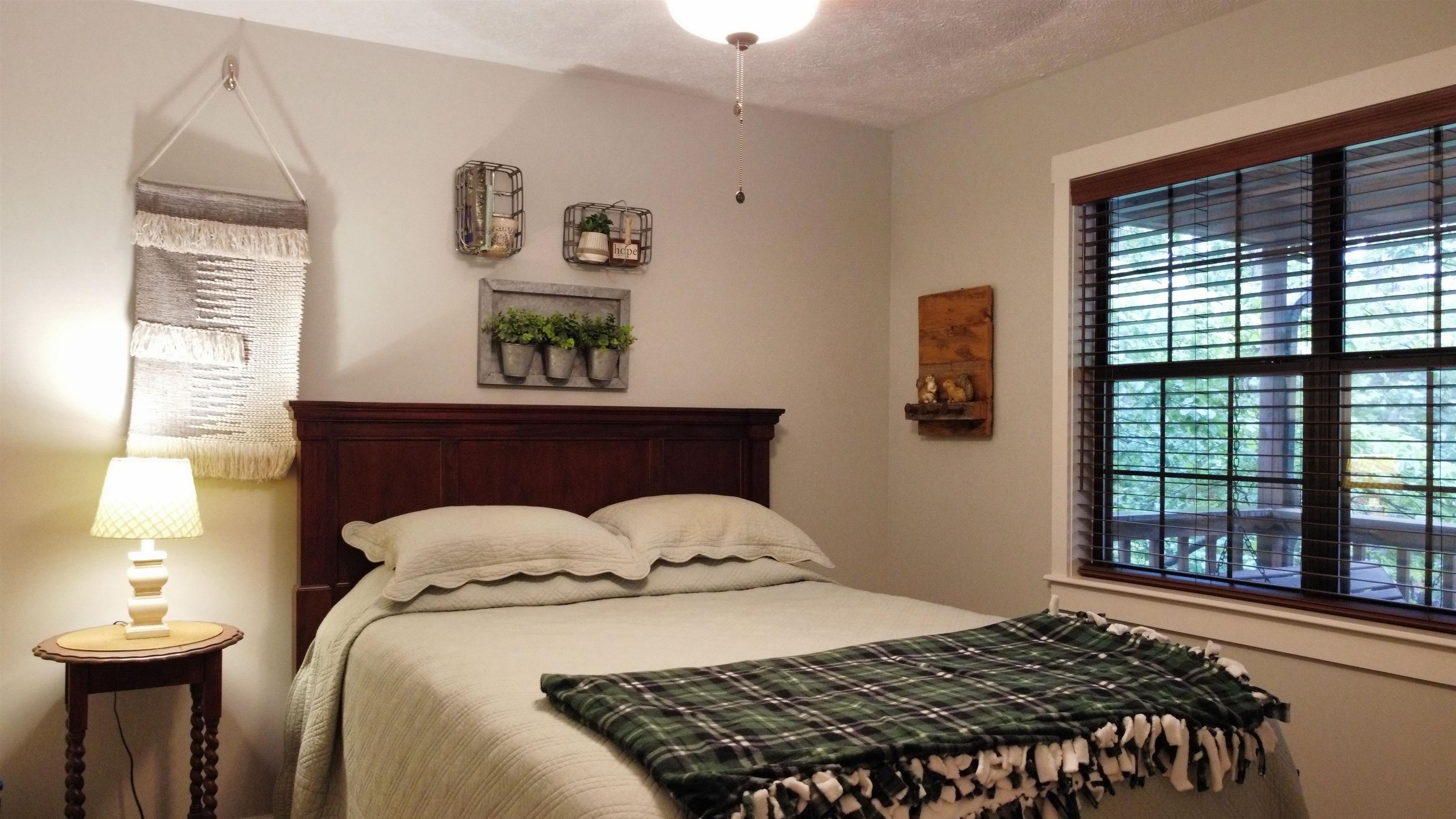 275 Bryson Harbor Road Counce, TN 38326 - Photo 20 of 23 Bright bedroom featuring a dark wood bed frame, light neutral wall paint, and a large window with dark wood trim and blinds