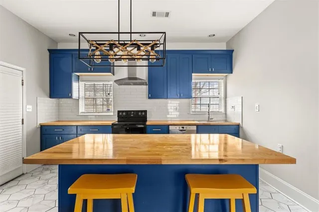 a kitchen with stainless steel appliances kitchen island a table chairs in it and wooden floors