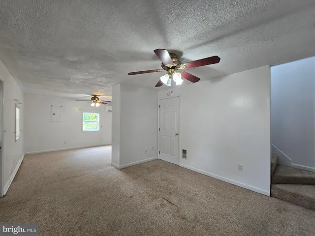 an empty room with windows and chandelier fan