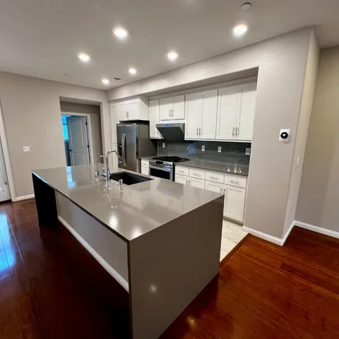 a kitchen with kitchen island stainless steel appliances a sink cabinets and wooden floor