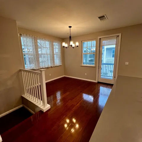 a view of an empty room with wooden floor and windows