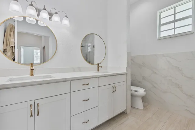 a bathroom with a double vanity sink mirror and toilet