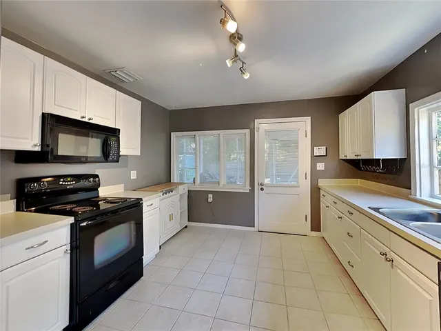 a large kitchen with a stove top oven a sink a microwave and cabinets